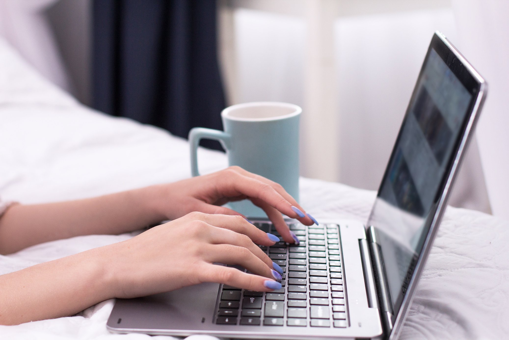 Young lady with laptop in bed